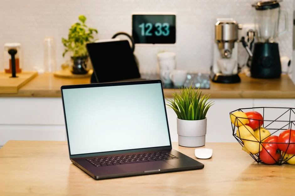 Person browsing the web on a MacBook at a wooden desk with a smartphone.